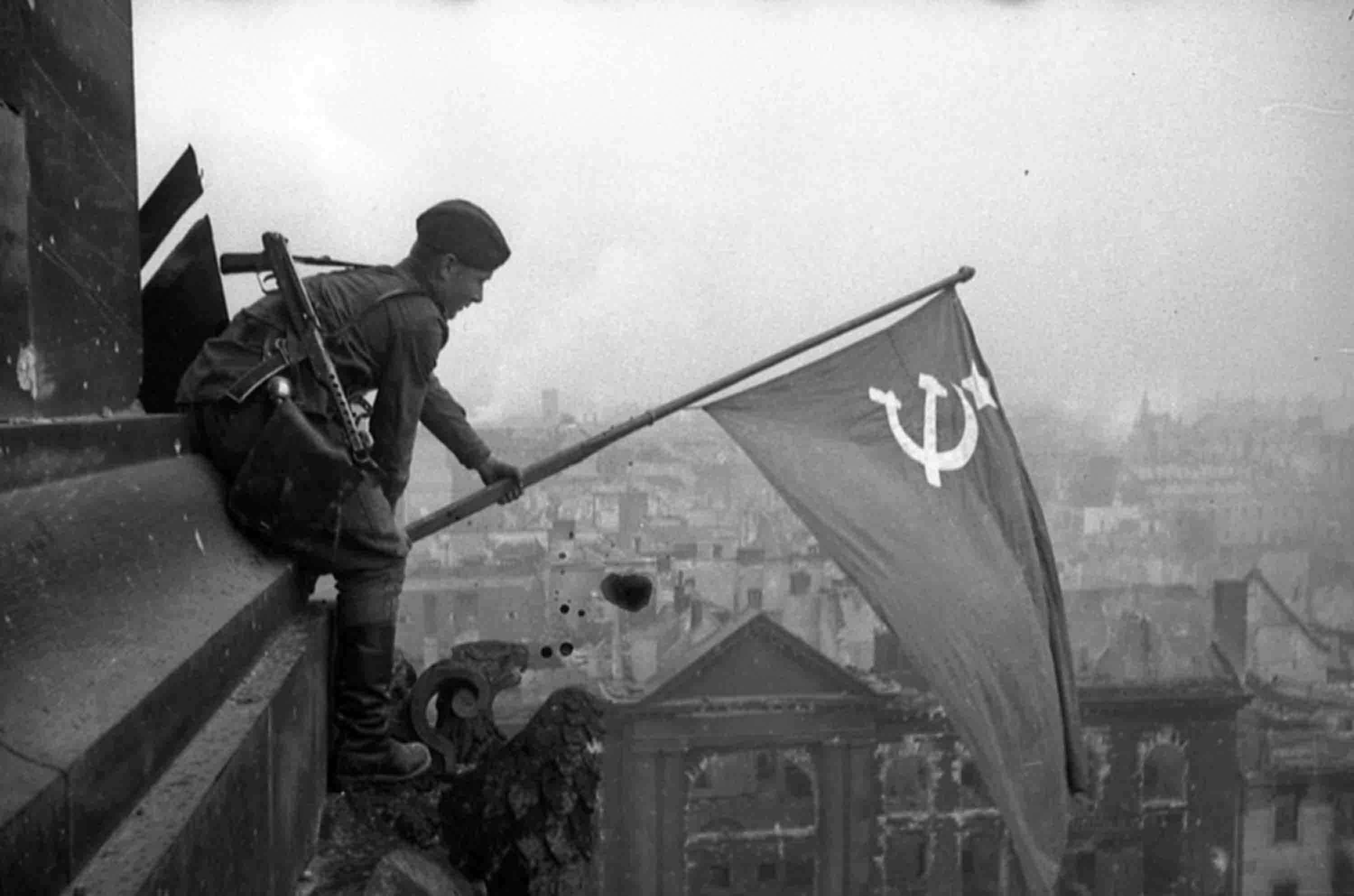 Советский солдат устанавливает флаг над Рейхстагом. На плече у него ППС-43. Фото © Из открытых источников