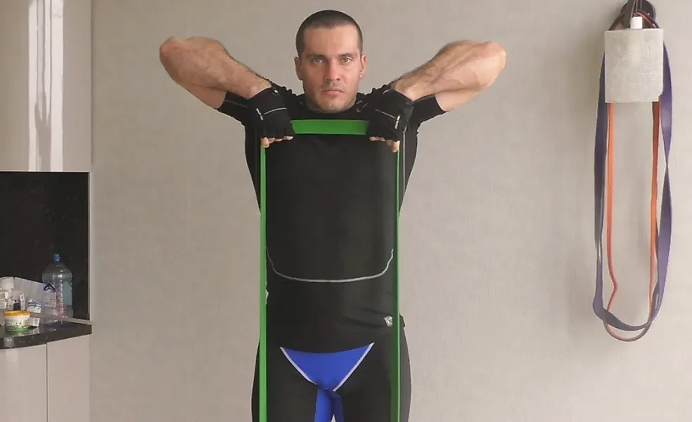 Тяга "резинки к подбородку" — это упражнение укрепляет плечи и верхнюю часть спины. Фото © Твой тренер / youtube