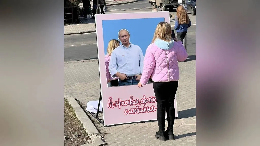 Девушка в Донецке делает фото у зеркала с изображением Путина. Обложка Telegram / ДМ | Донбасс Медиа