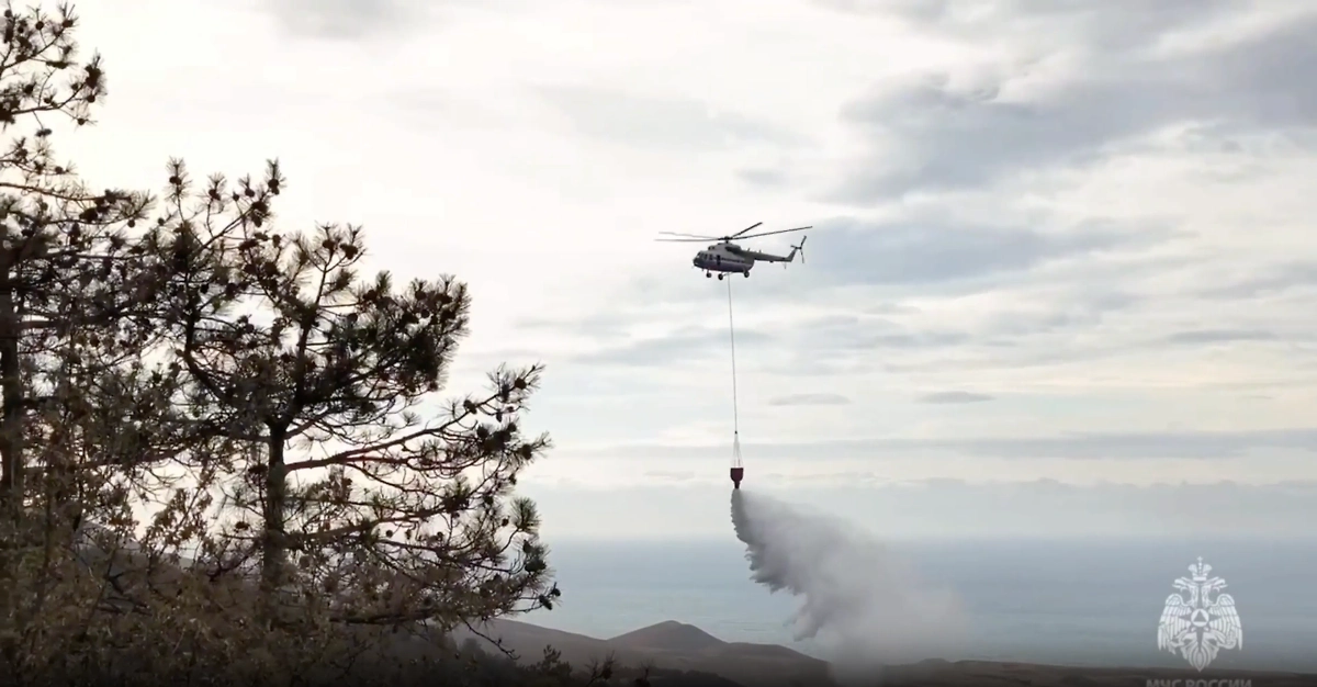 Вертолёт МЧС сбрасывает воду над пламенем. Фото © Telegram / МЧС России