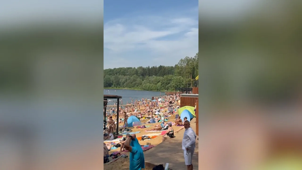 Пляж «Синичка» в Красногорске забит людьми, некоторые загорают на лавочке. Обложка © Telegram / SHOT