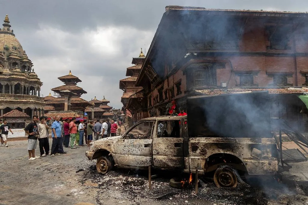 Местные жители возле правительственного автомобиля, сгоревшего во время столкновений протестующих с полицией в Катманду. Фото © EPA/NARENDRA SHRESTHA 