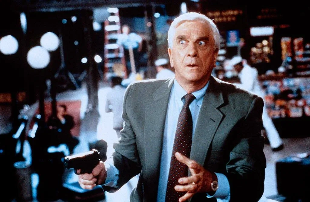 Первая часть «Голого пистолета» стала эталоном абсурдной комедии. Фото © Кадр из фильма «Голый пистолет», режиссёр Дэвид Цукер, сценарист Джерри Цукер и др. / Kinopoisk