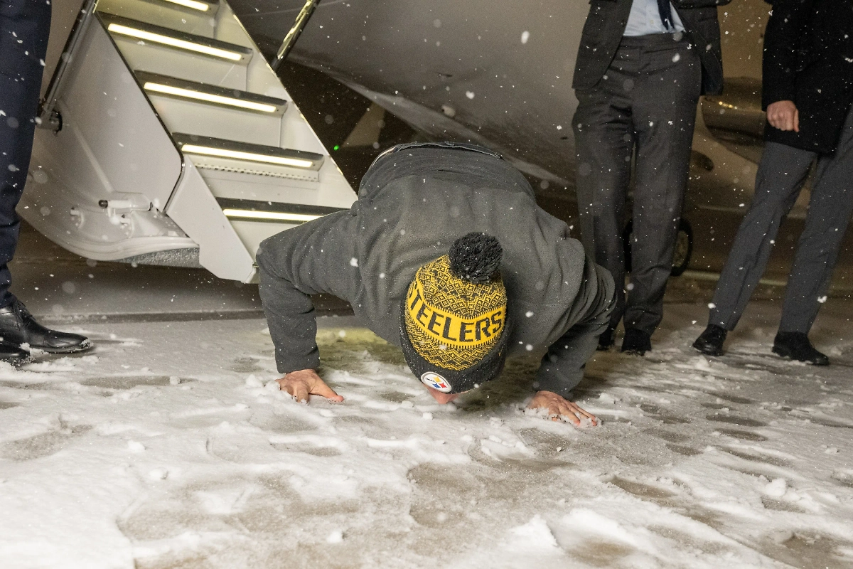 Бывший заключённый целует снег по прилёте. Фото © X / President Donald J. Trump