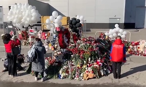 Кинологи с собаками проверяют стихийный мемориал у здания "Крокуса"