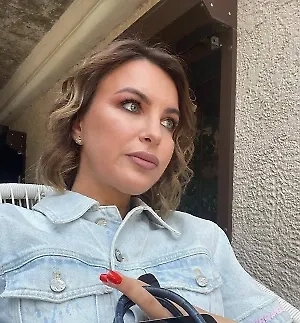 На девушке надето изысканное кольцо, выполненное известным брендом Graff, который славится своими уникальными ювелирными изделиями и высоким качеством. Основной материал этого украшения — платина, которая отличается своей прочностью, долговечностью и благородным серебристым оттенком. &lt;...&gt;  В центре кольца расположен крупный бриллиант огранки кушон весом 3 карата, который привлекает внимание своей яркостью и игрой света.