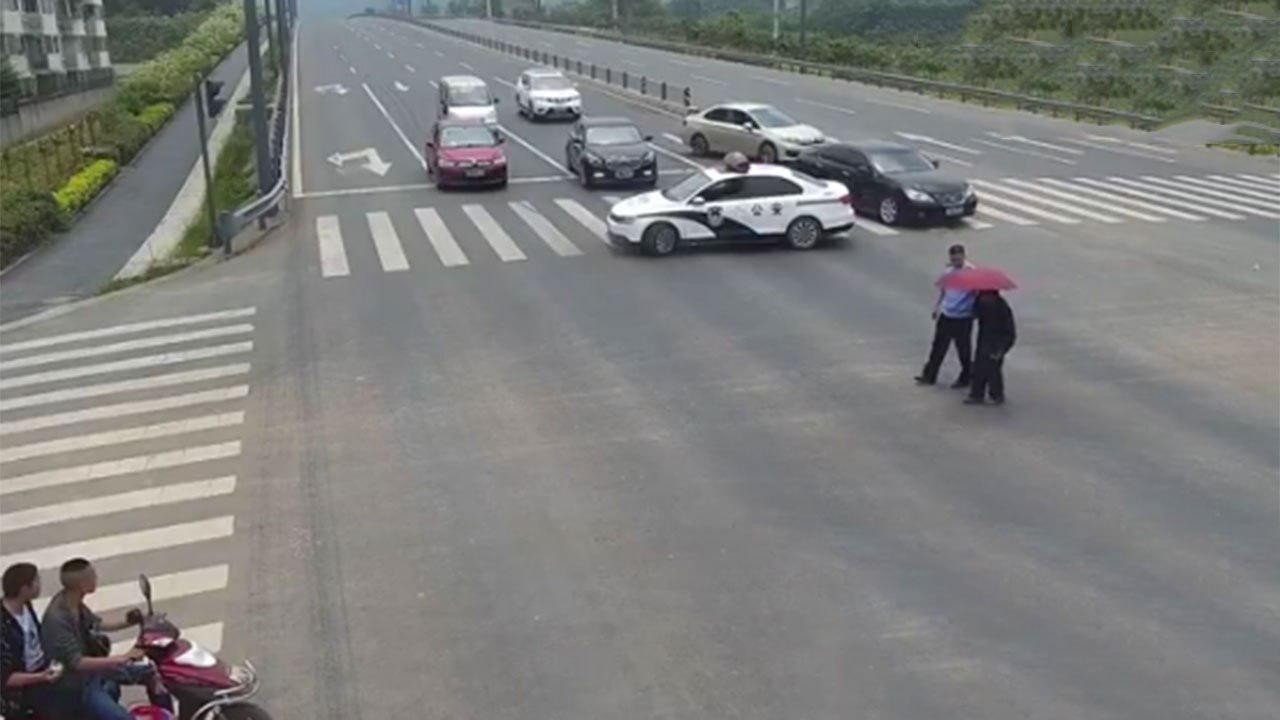 Полицейский переводит пожилого мужчину через дорогу. Фото: кадр из видео Twitter/@PDChina