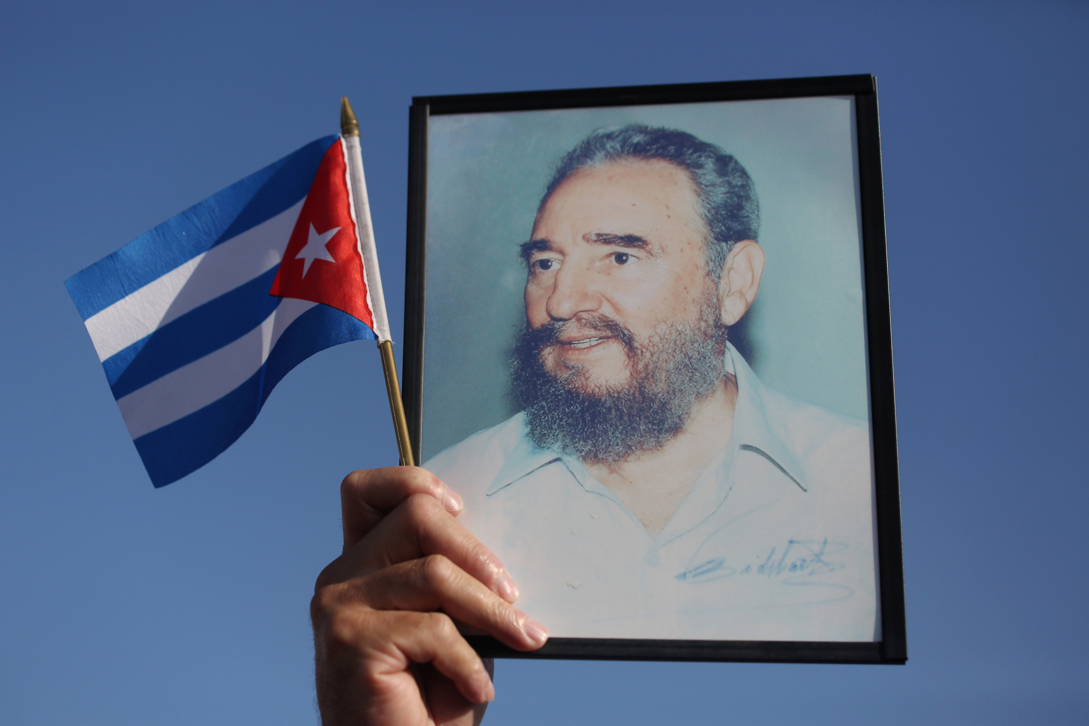 Кубинский флаг на фоне портрета бывшего лидера страны Фиделя Кастро. Фото: &copy;&nbsp;REUTERS/Alexandre Meneghini 