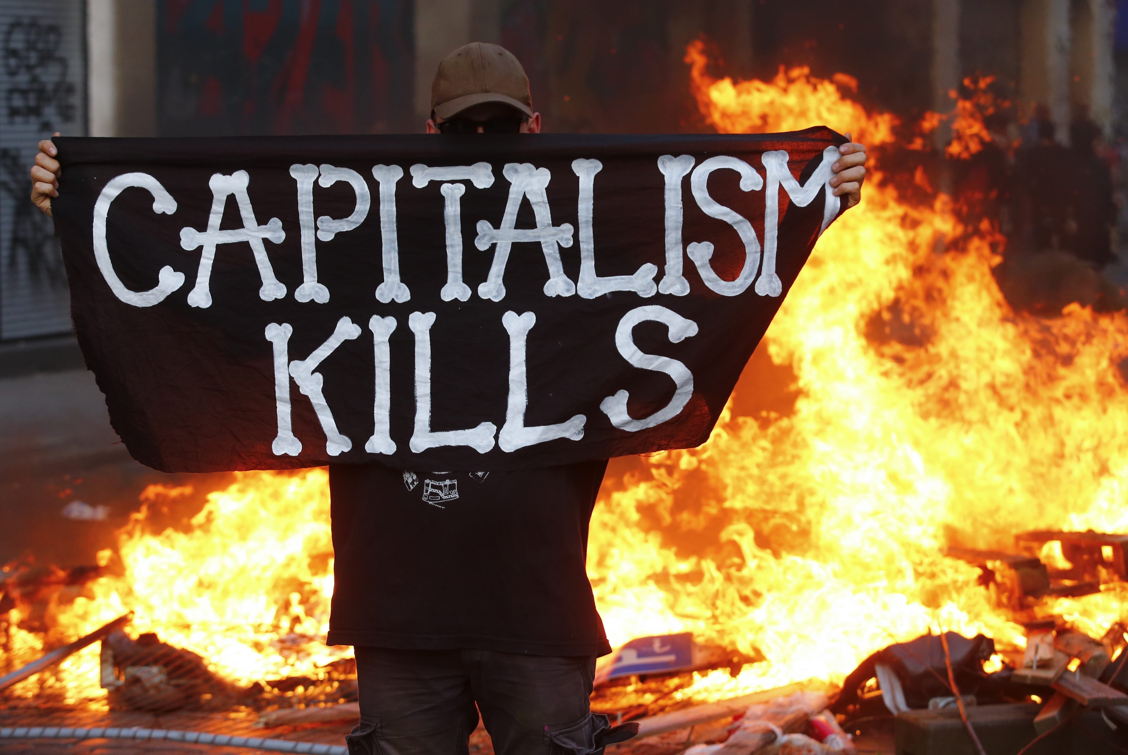 Участник протестов в Гамбурге с флагом "Капитализм убивает". Фото: &copy; REUTERS/Hannibal Hanschke