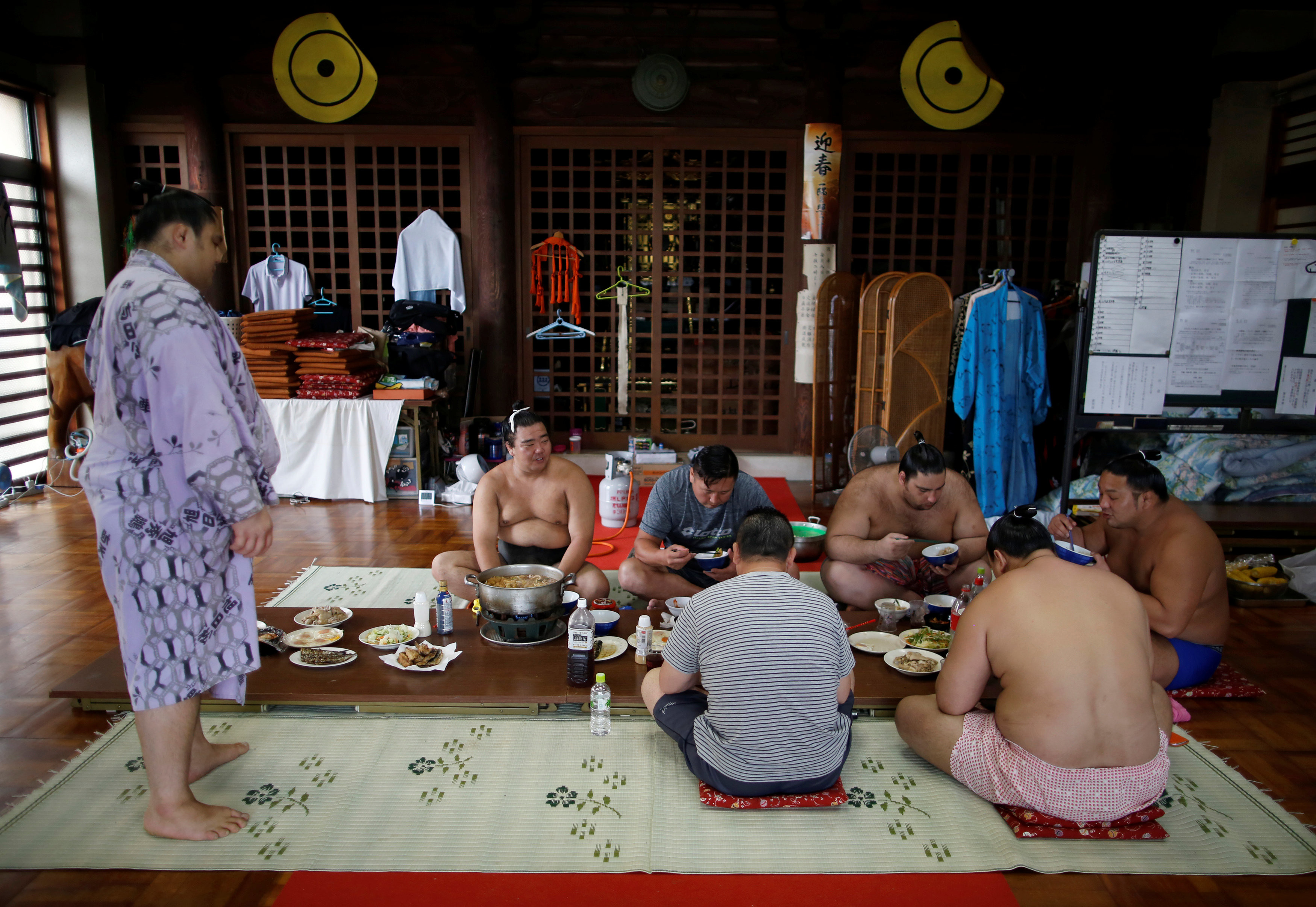 Монгольский борец и тренер Томозуна Ояката и его борцы едят в главном зале храма Ганджоджи. Фото © REUTERS/Issei Kato