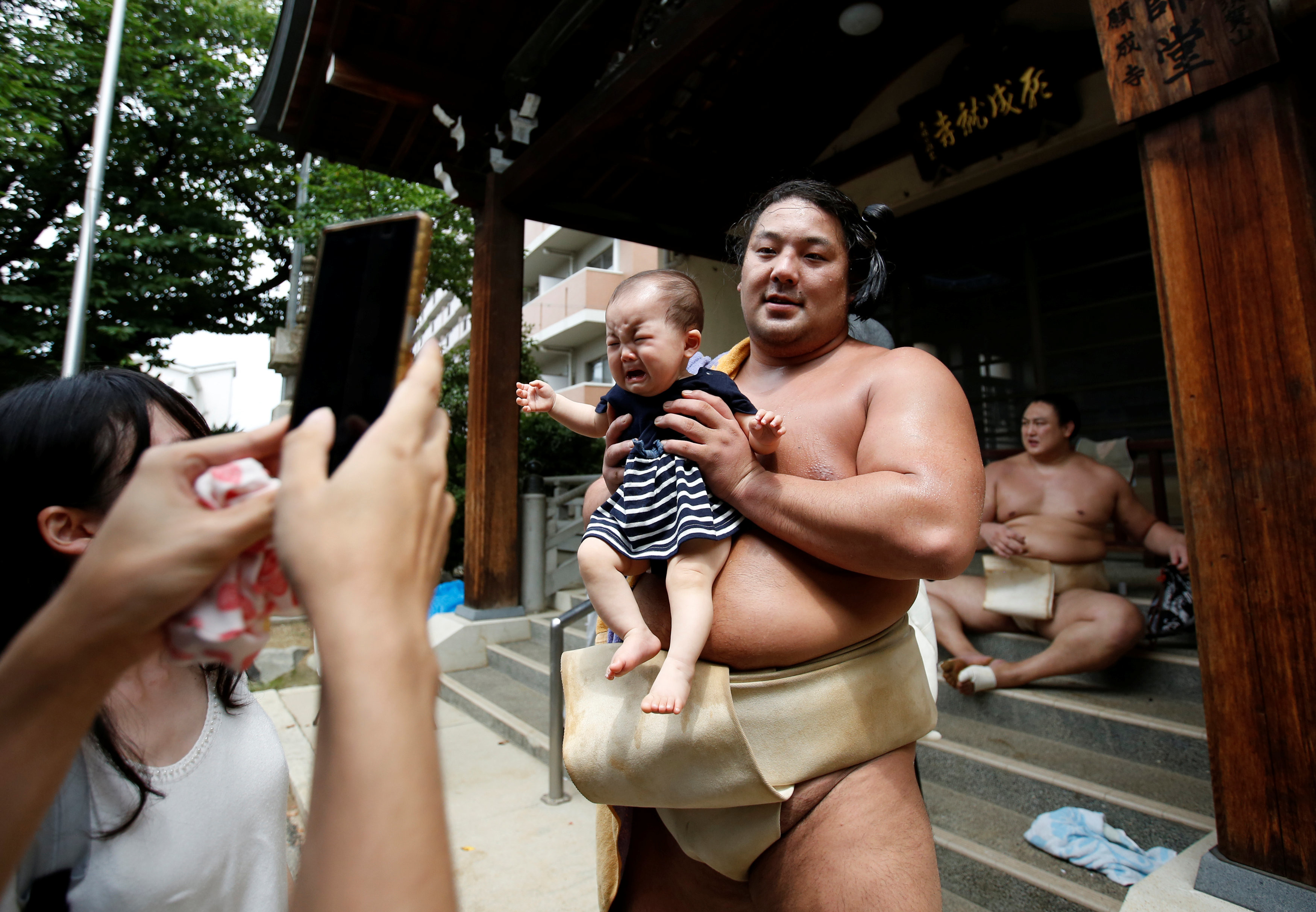 Борец сумо позирует для фотографии с ребёнком после тренировки в храме Ганджоджи в Нагое. Фото © REUTERS/Issei Kato