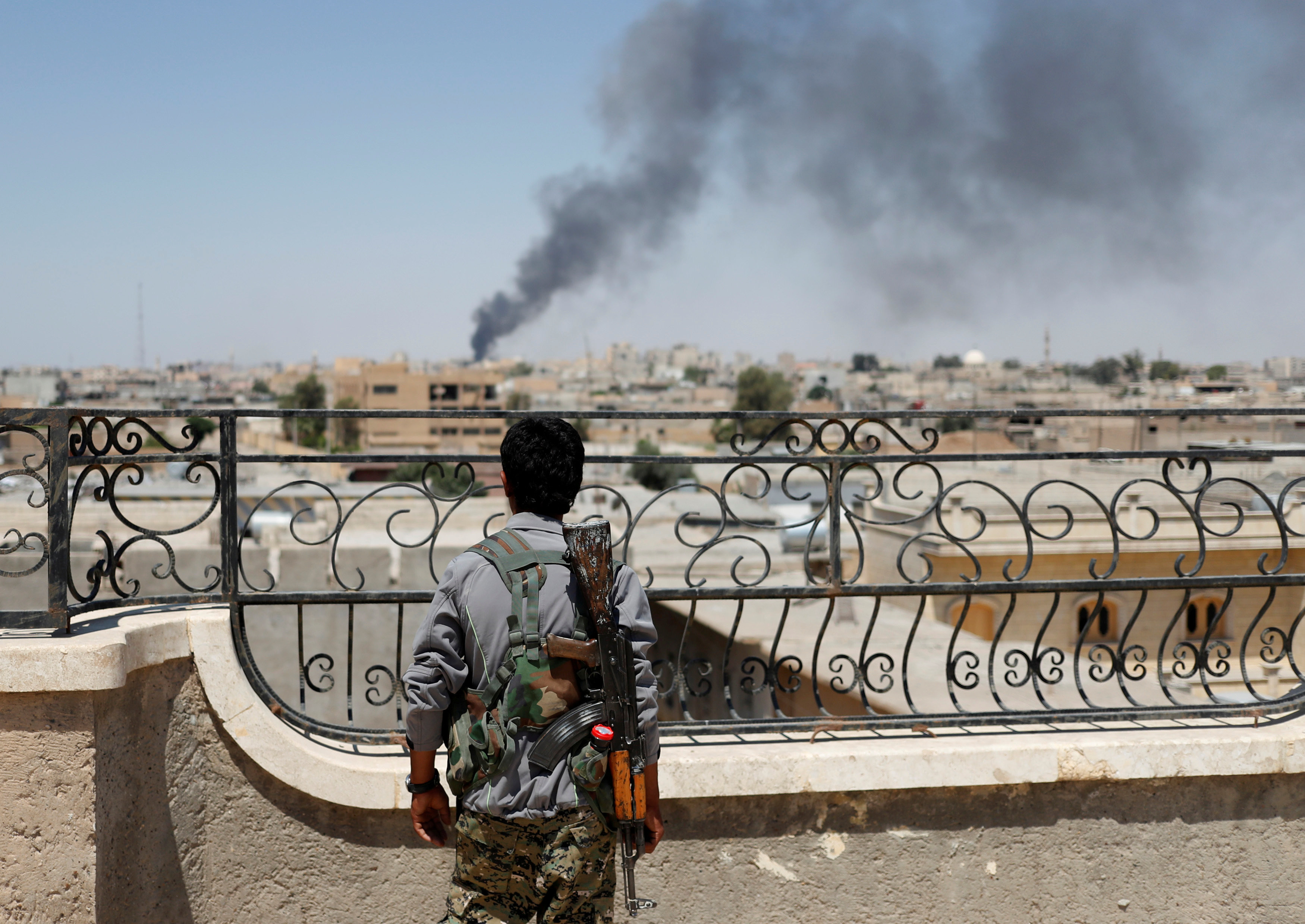 Курдский боец смотрит на город Ракка, подвергшийся бомбардировке. Фото: &copy;&nbsp;REUTERS/Goran Tomasevic