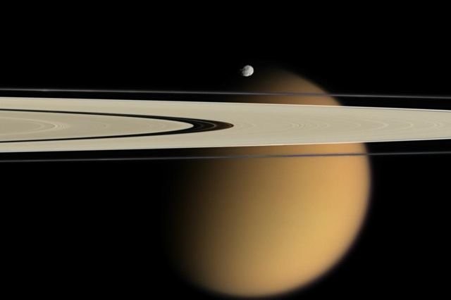 Титан, самый большой спутник Сатурна, за кольцами планеты.&nbsp;На переднем плане виден гораздо меньший по размерам спутник &mdash; Эпиметей. Фото: &copy;&nbsp;NASA/JPL/Space Science Institute