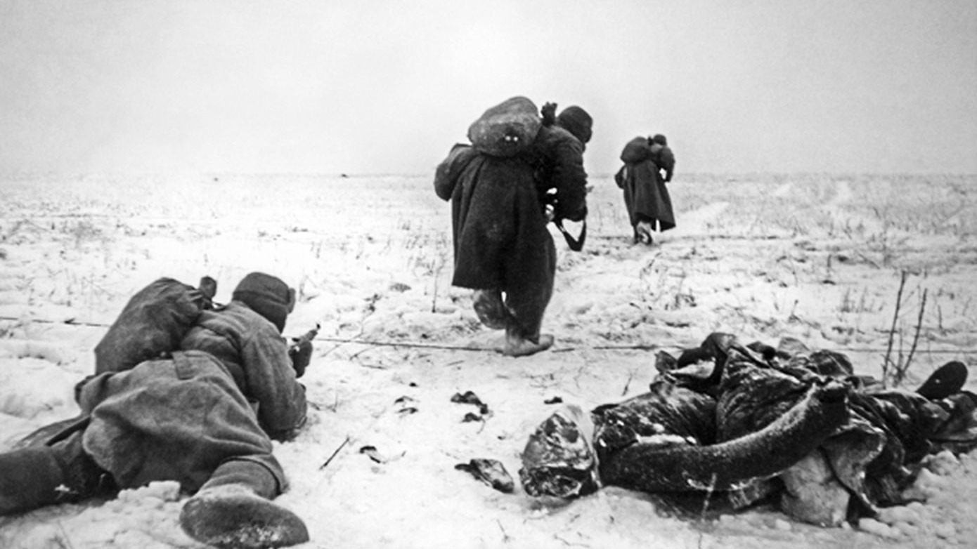Красноармейцы продвигаются по полю возле окоченевшего тела немецкого солдата под Сталинградом. Фото: © Военный альбом