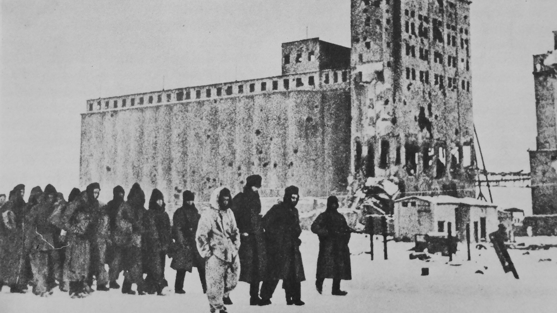 Красноармеец конвоирует колонну немецких военнопленных у здания элеватора в Сталинграде. Фото: © Военный альбом