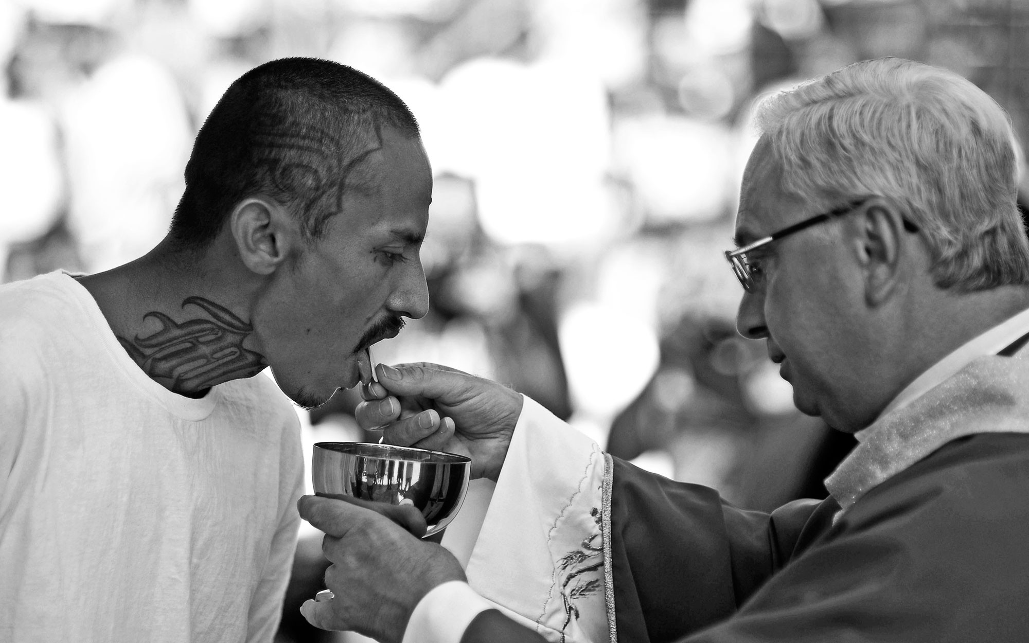 Член банды Mara Salvatrucha получает причастие от священника. Фото: © REUTERS/Ulises Rodriguez
