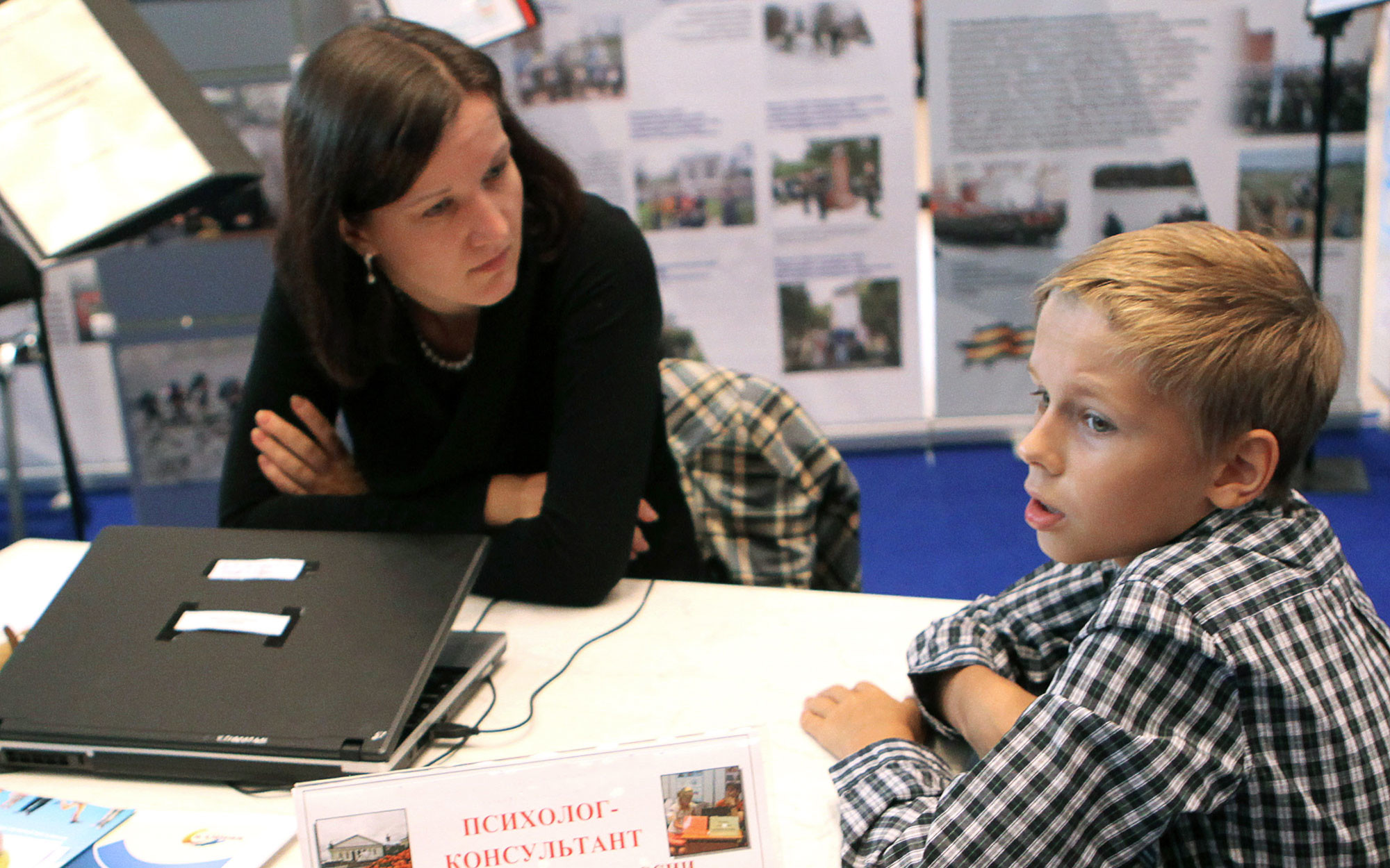 Психолог-консультант беседует с мальчиком на выставке. Фото: ©РИА Новости / Владимир Песня