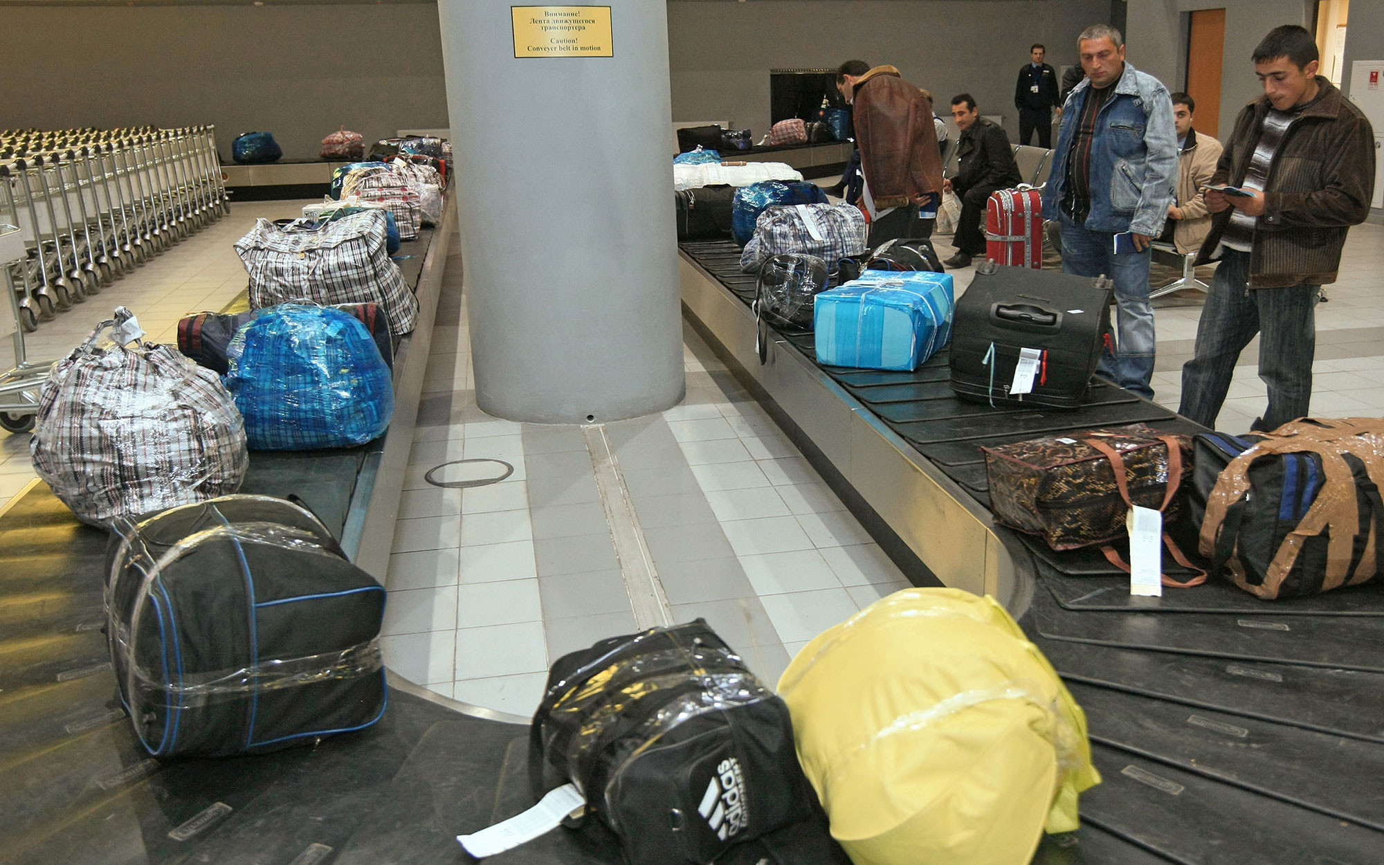 Можно сдать в багаж ноутбук. Чемодан в аэропорту. Упаковка багажа для самолета. Упаковка чемодана в аэропорту. Упаковка сумки в аэропорту.
