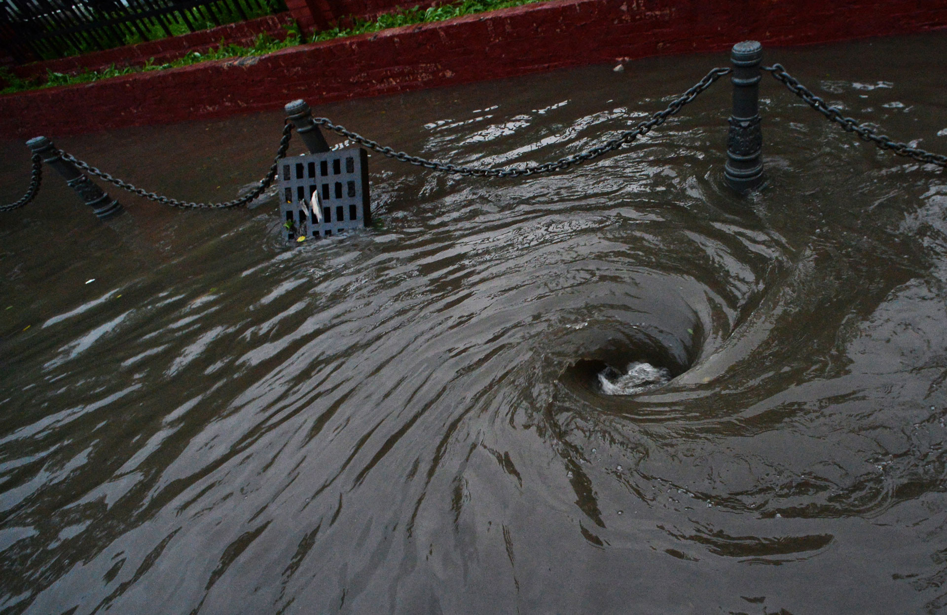 Вода уходит в ливневую канализацию на улице, затопленной ливнем. Фото: © РИА Новости/Виталий Аньков