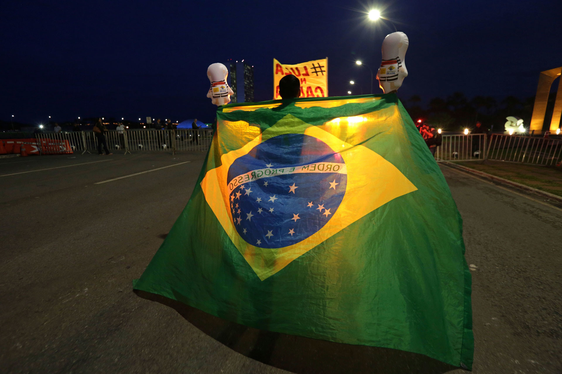Демонстрант против бывшего президента Бразилии Луиса Инасио Лулы да Силвы держит бразильский флаг за пределами Национального конгресса Бразилии. Фото: © AP Photo / Eraldo Peres