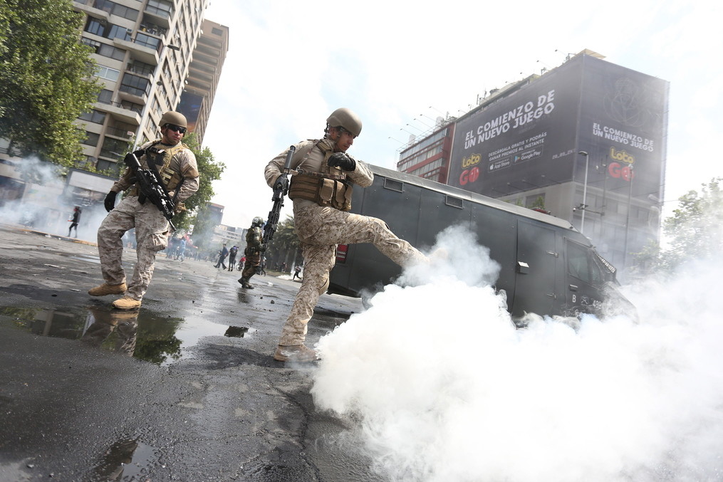 Протестующие закидывают чилийских военных дымовыми шашками. Фото © ТАСС / EPA / ELVIS GONZALEZ
