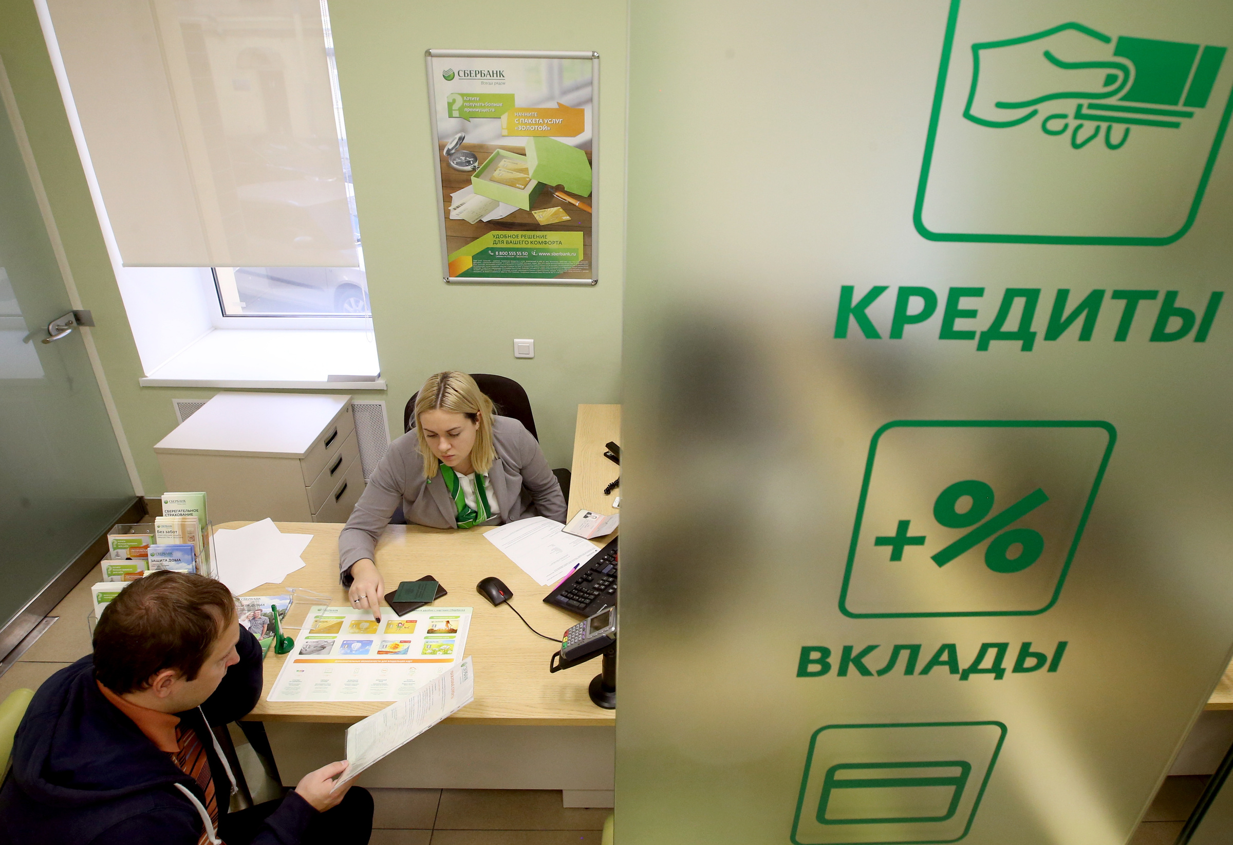 Сотрудница одного из отделений банка во время общения с клиентом. Фото © ТАСС / Петр Ковалев