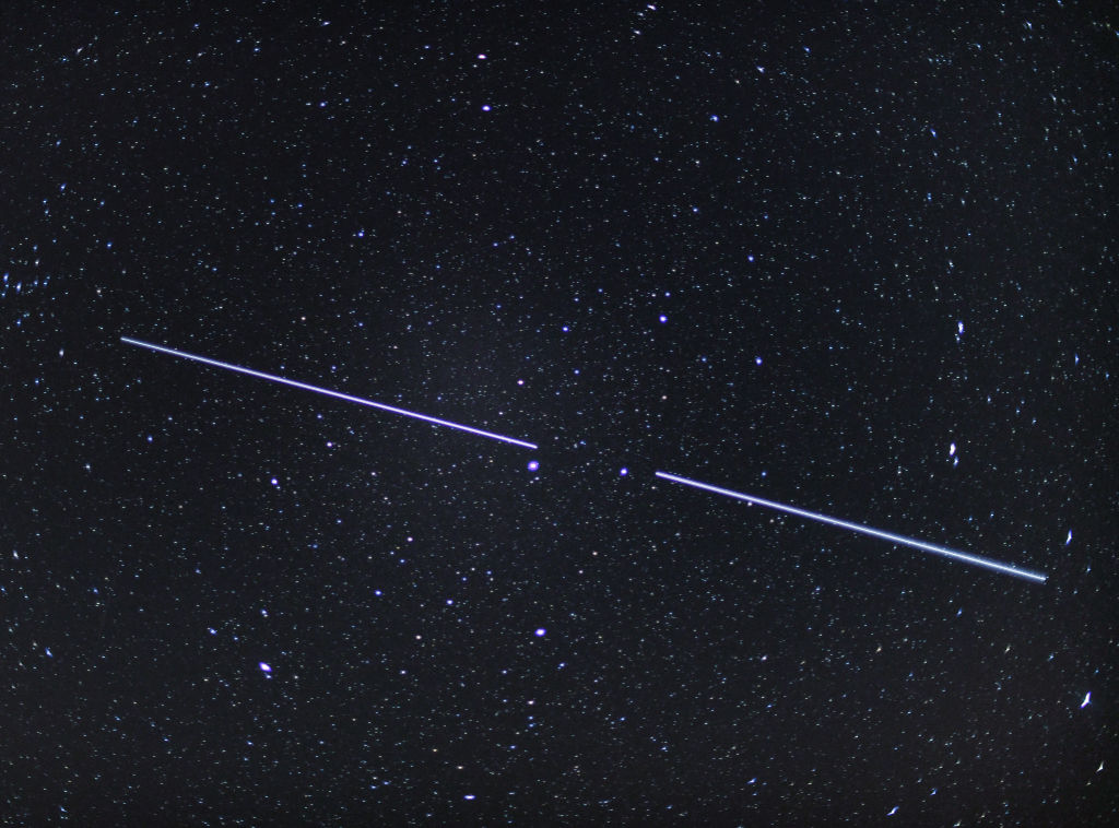 Два спутника Starlink можно увидеть как полосы света в ночном небе (снято с выдержкой 15 секунд). Фото © Getty Images / Patrick Pleul / picture alliance