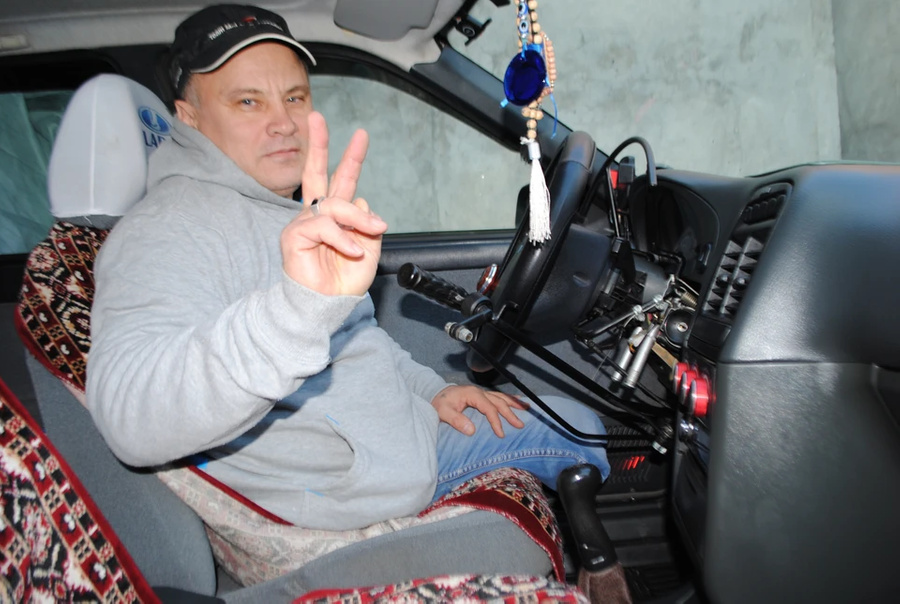 Юрий за рулём автомобиля, переоборудованного для людей с ограниченными возможностями. Обложка © kp.ru