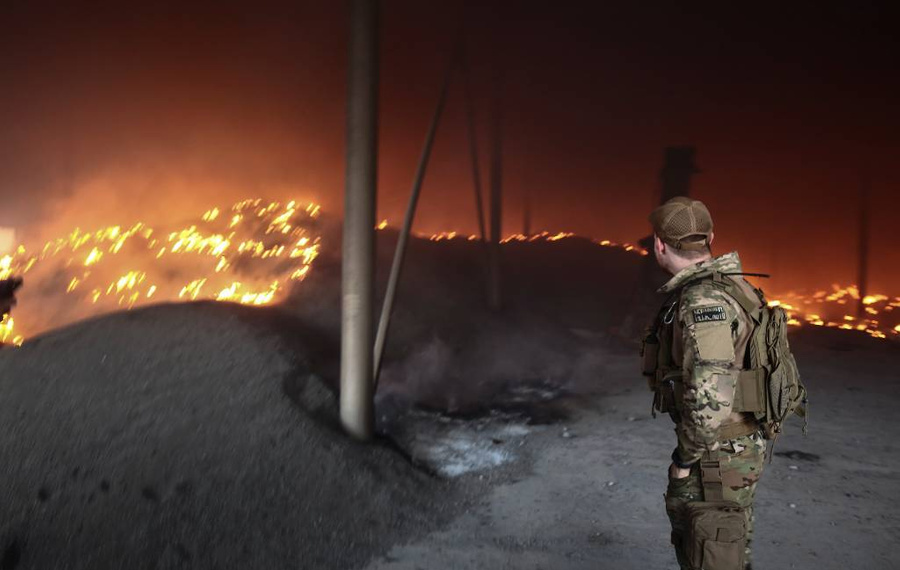 Украинский военнослужащий смотрит на горящее после обстрела здание недалеко от города Бахмута. Фото © ТАСС / EPA / STR