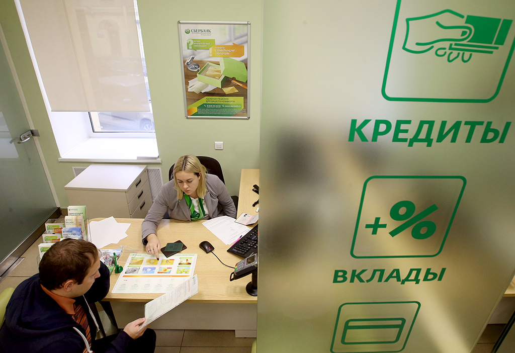 Сотрудница одного из отделений Сбербанка во время общения с клиентом. Фото © ТАСС / Пётр Ковалёв
