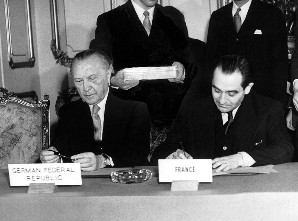 Премьер-министр Франции Пьер Мендес Франс (справа) и канцлер ФРГ Конрад Аденауэр (слева) подписывают договор о перевооружении Западной Германии и условия её вступления в НАТО в Ланкастер-Хаусе в Лондоне 3 октября 1954 года. Фото © Getty Images / Keystone-France / Gamma-Keystone