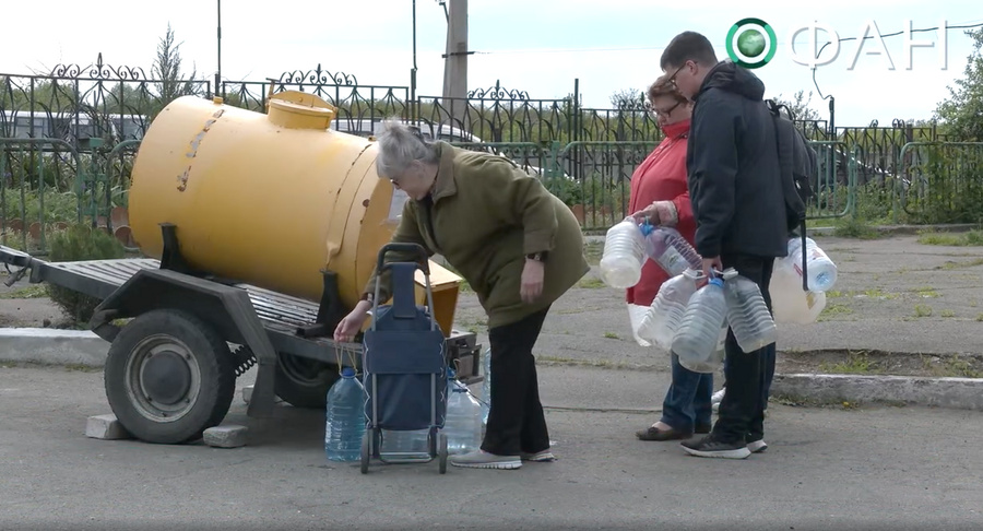 Жители Донецка получают воду, которую специально привезли волонтёр с сыном. Кадр из видео © РИА ФАН