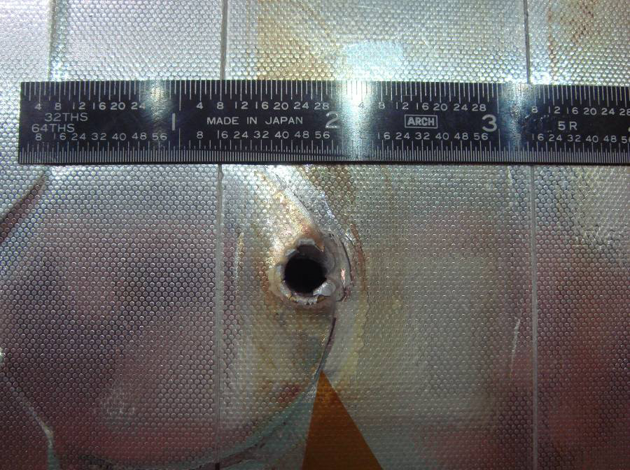 Отверстие в панели радиатора, образовавшееся в результате столкновения с космическим мусором. Фото © Wikipedia