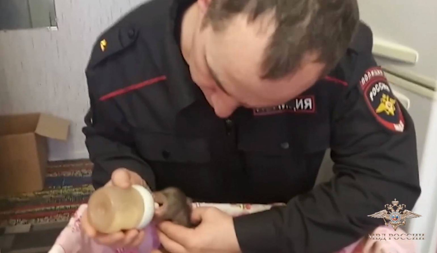 Сотрудник полиции кормит молоком медвежонка. Обложка © МВД РФ