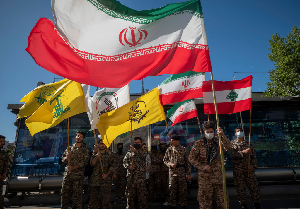 Члены военизированных формирований "Басидж" держат иранский флаг, ливанский флаг, флаг Хашд-Шаби, флаг бригады "Фатемиюн" сил "Кудс" и флаг ливанской "Хезболлы". Фото © Getty Images / Morteza Nikoubazl / NurPhoto