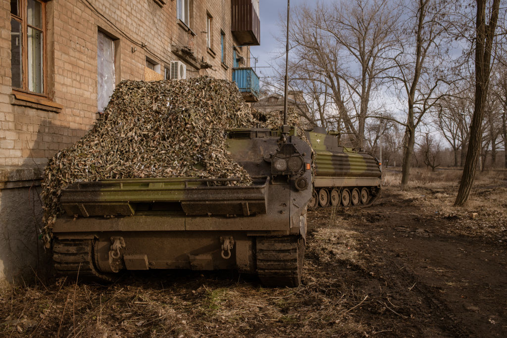 Украинские солдаты прячутся за двумя БМП Bradley под камуфляжем в Часове Яре, Донецкая область, Украина, 7 марта 2023 года. Фото © Getty Images / Andre Luis Alves / Anadolu Agency