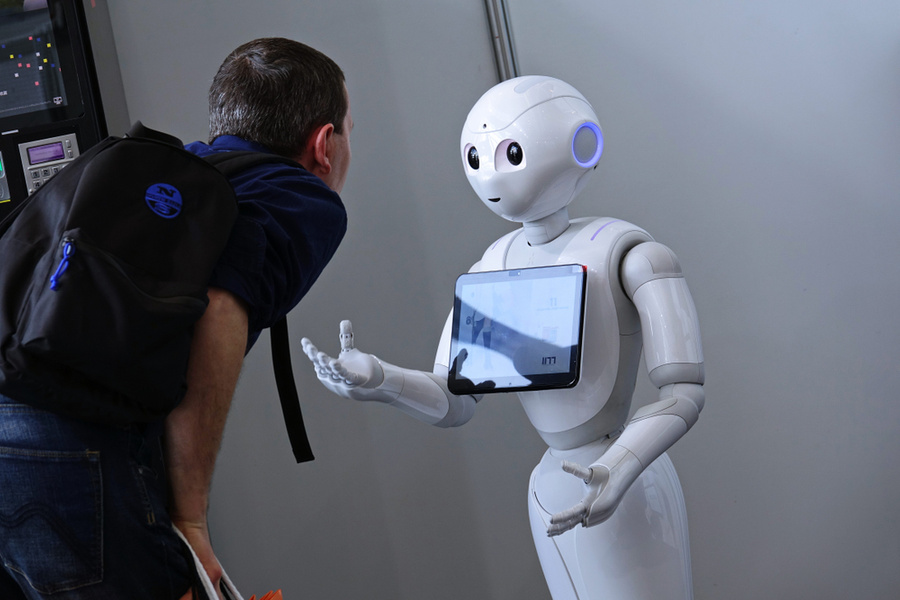 Посетитель выставки разговаривает с роботом. Обложка © Shutterstock
