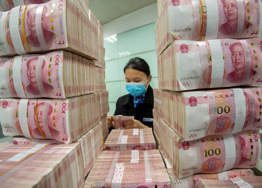 Клерк пересчитывает банкноты в юанях. Фото © Getty Images / Future Publishing