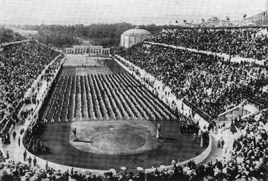 Вид спортсменов, стоящих рядами, и толпы, заполняющие стадион на Олимпийских играх 1896 года в Афинах, Греция. Фото © Getty Images / Hulton Archive