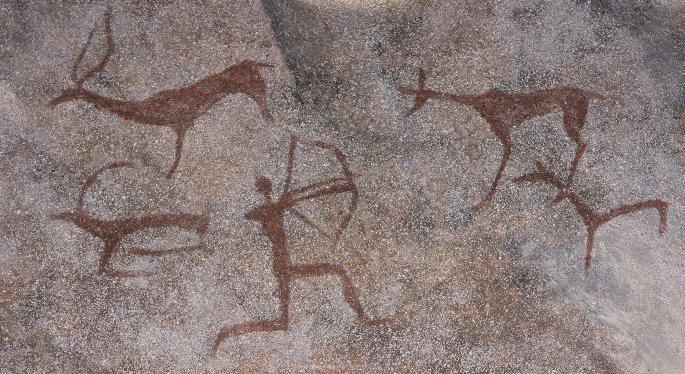 Рисунок животных и охотник на каменной стене пещеры. Краски охра. Древний доисторический неандерталь. Фото © Shutterstock