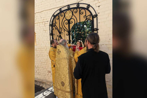 Прихожане причащаются через решётку ворот храма у Киево-Печерской лавры